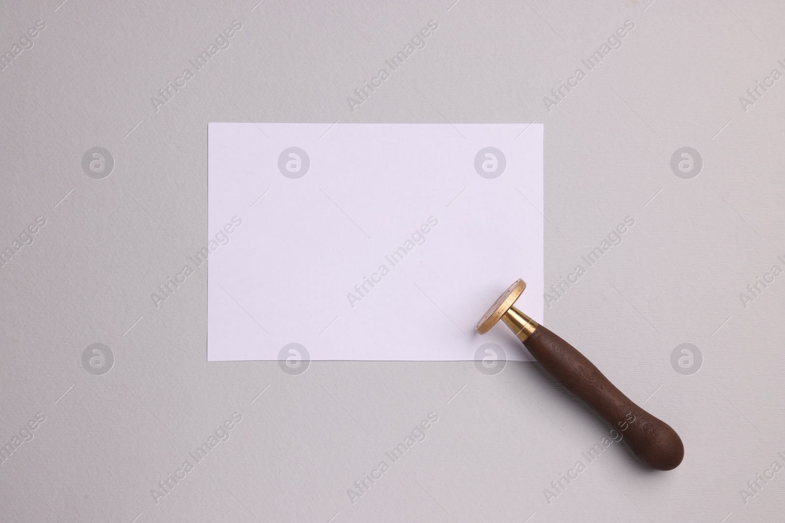 Photo of One stamp tool and sheet of paper on light grey background, top view. Space for text