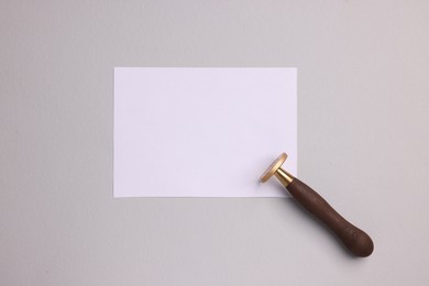 One stamp tool and sheet of paper on light grey background, top view. Space for text