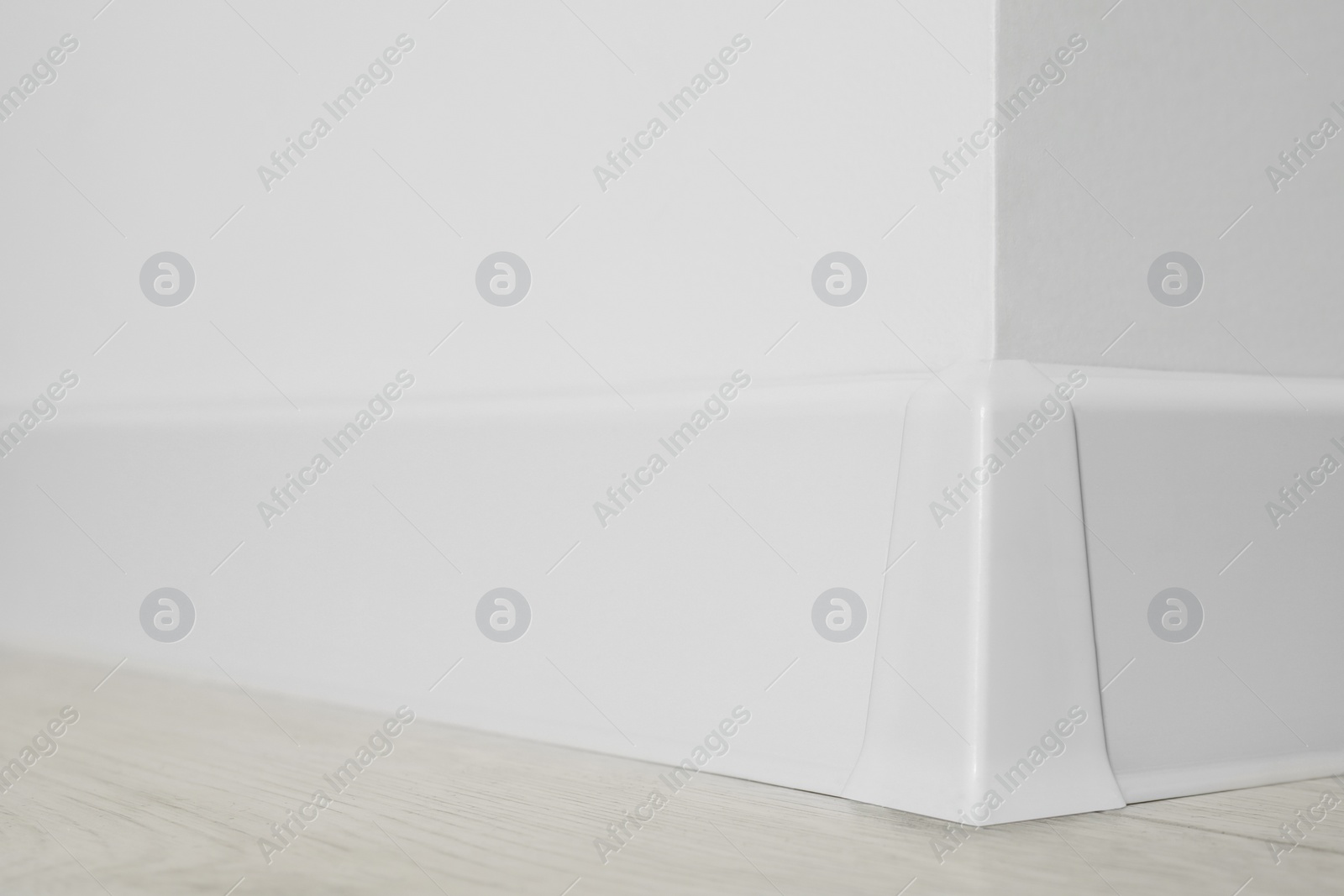 Photo of White plinth with connector on laminated floor near wall indoors, closeup