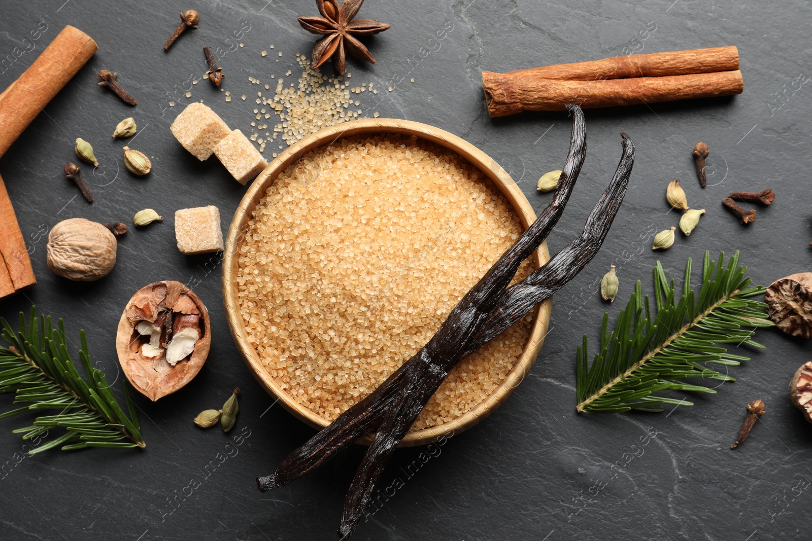 Photo of Different aromatic spices and fir branches on dark textured table, flat lay