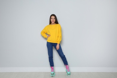 Full length portrait of young woman with roller skates near color wall