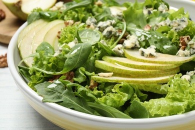 Photo of Fresh salad with pear on white wooden table, closeup