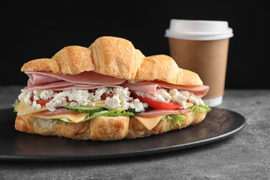 Photo of Tasty croissant sandwich with ham on grey table