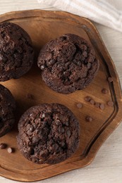 Delicious chocolate muffins on white wooden table, top view