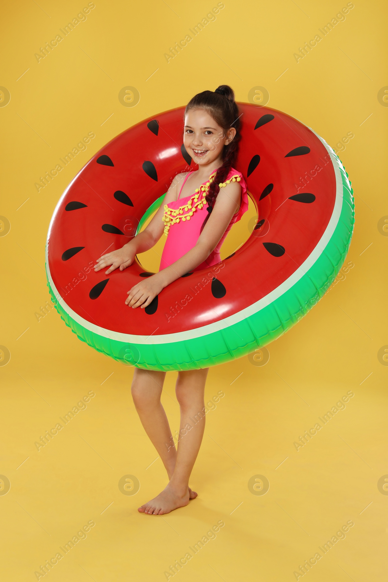 Photo of Cute little girl with bright inflatable ring on yellow background