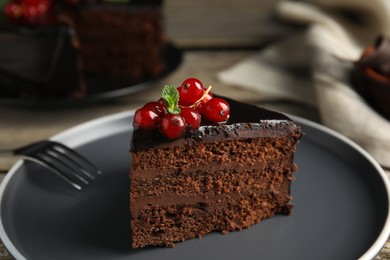 Piece of tasty homemade chocolate cake with berries and mint on plate, closeup