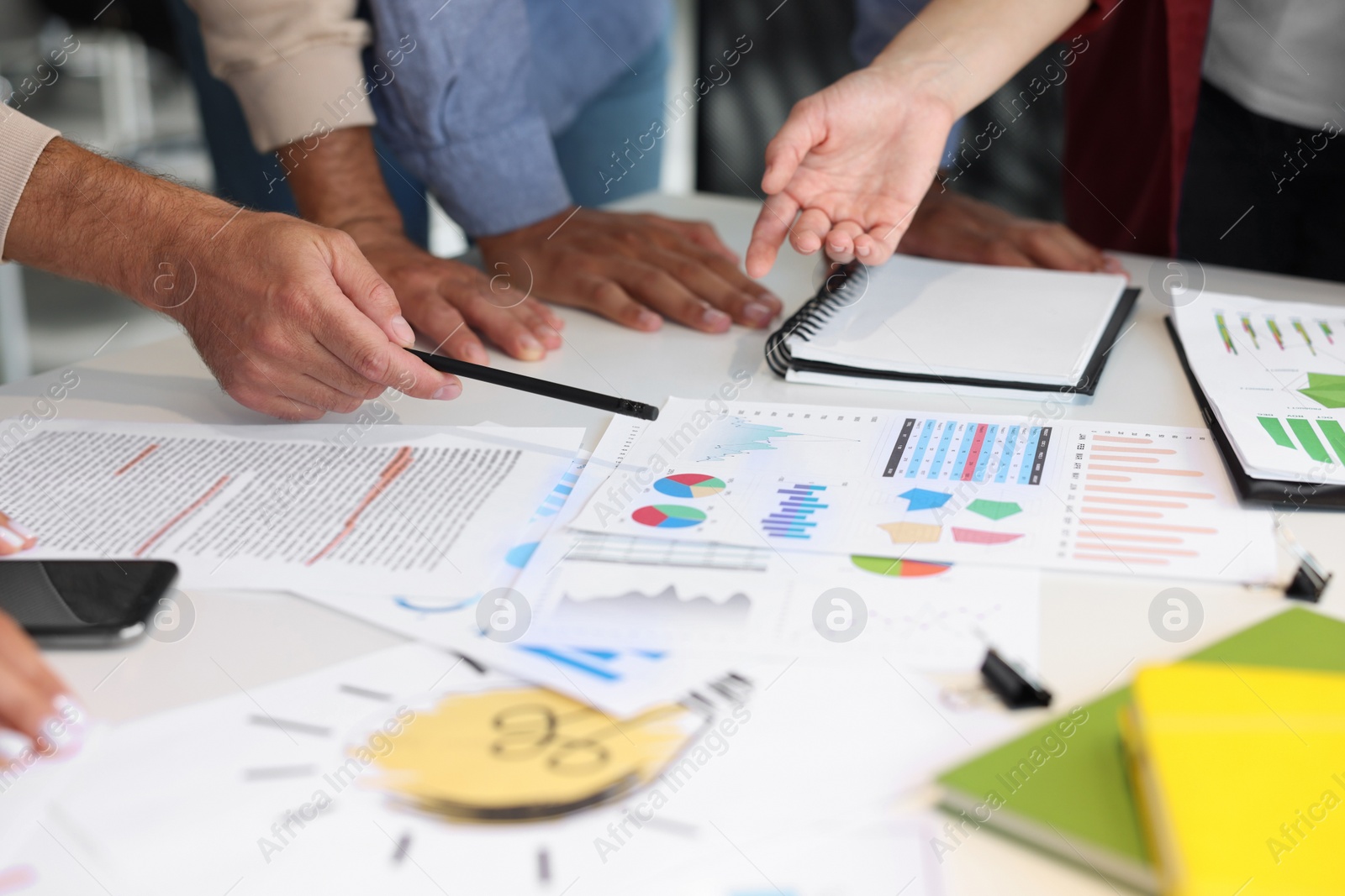 Photo of Team of employees working with charts at table, closeup. Startup project