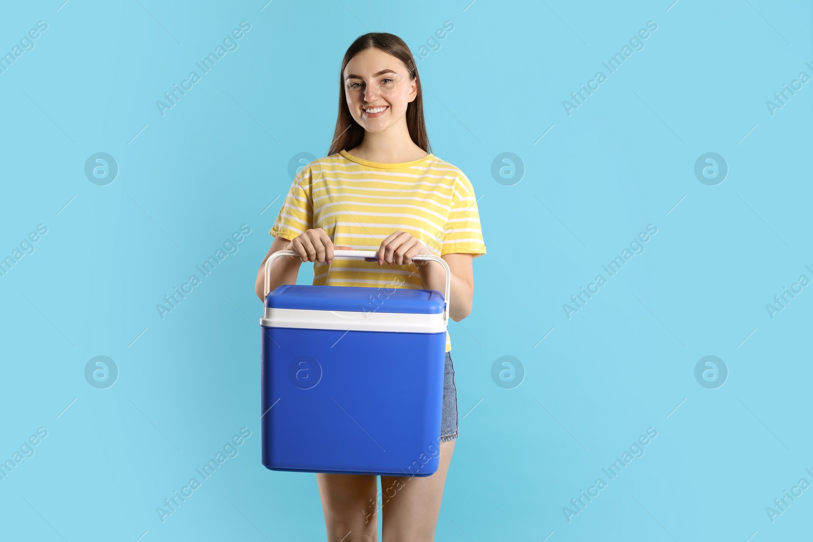 Photo of Happy young woman with plastic cool box on light blue background