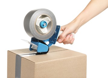Photo of Woman applying adhesive tape on box with dispenser against white background, closeup