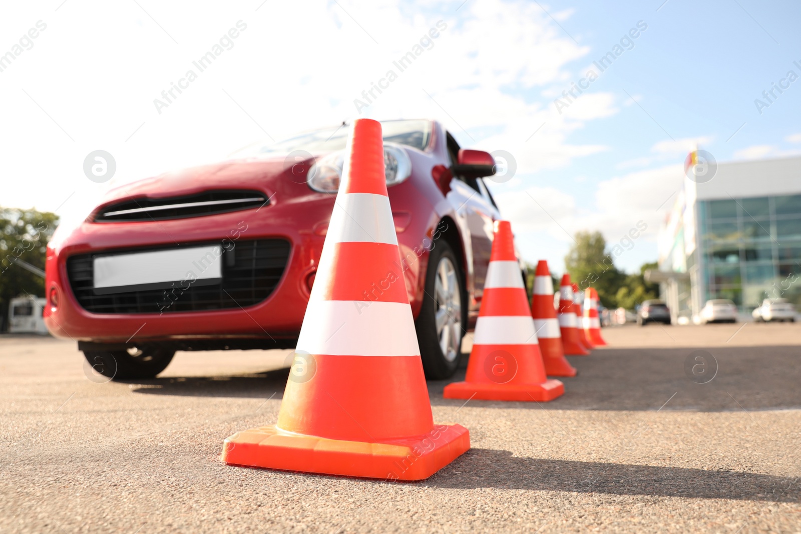 Photo of Traffic cones near red car outdoors. Driving school exam