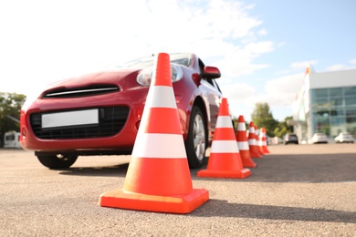 Traffic cones near red car outdoors. Driving school exam