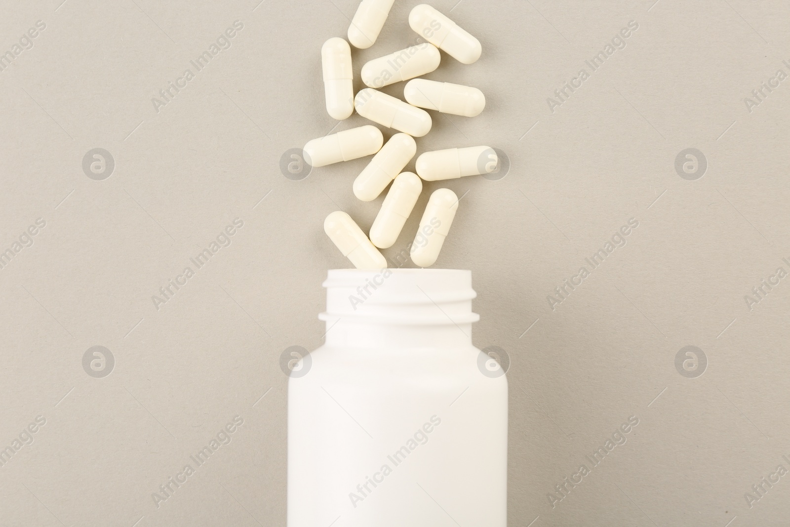 Photo of Bottle and vitamin capsules on light background, top view