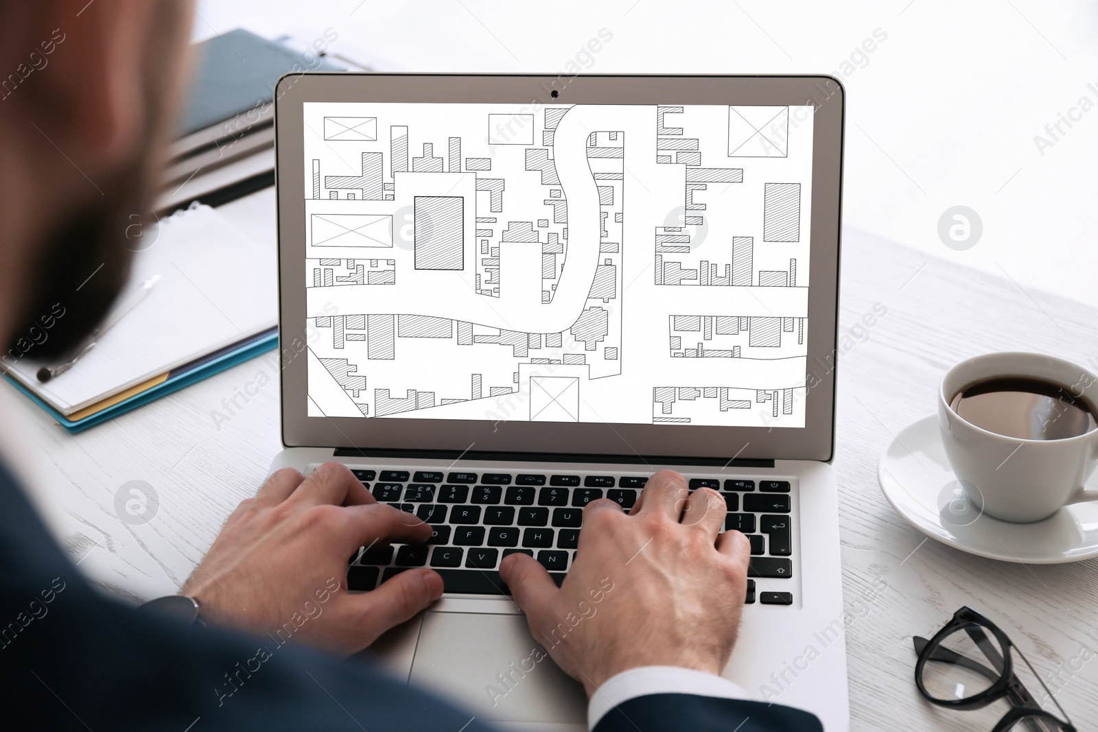 Image of Man analyzing cadastral map on laptop at table, closeup 