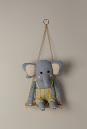 Photo of Shelf with cute toy elephant on beige wall. Child's room interior element