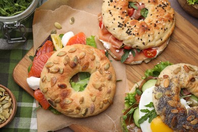 Tasty bagel sandwiches on wooden board, top view