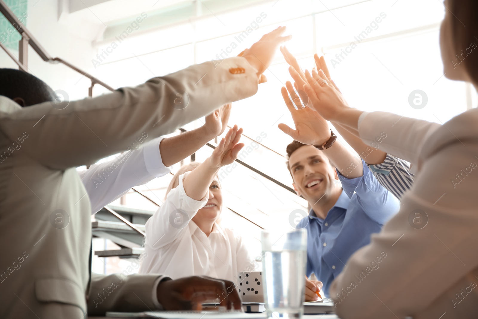 Photo of People putting hands together indoors. Unity concept