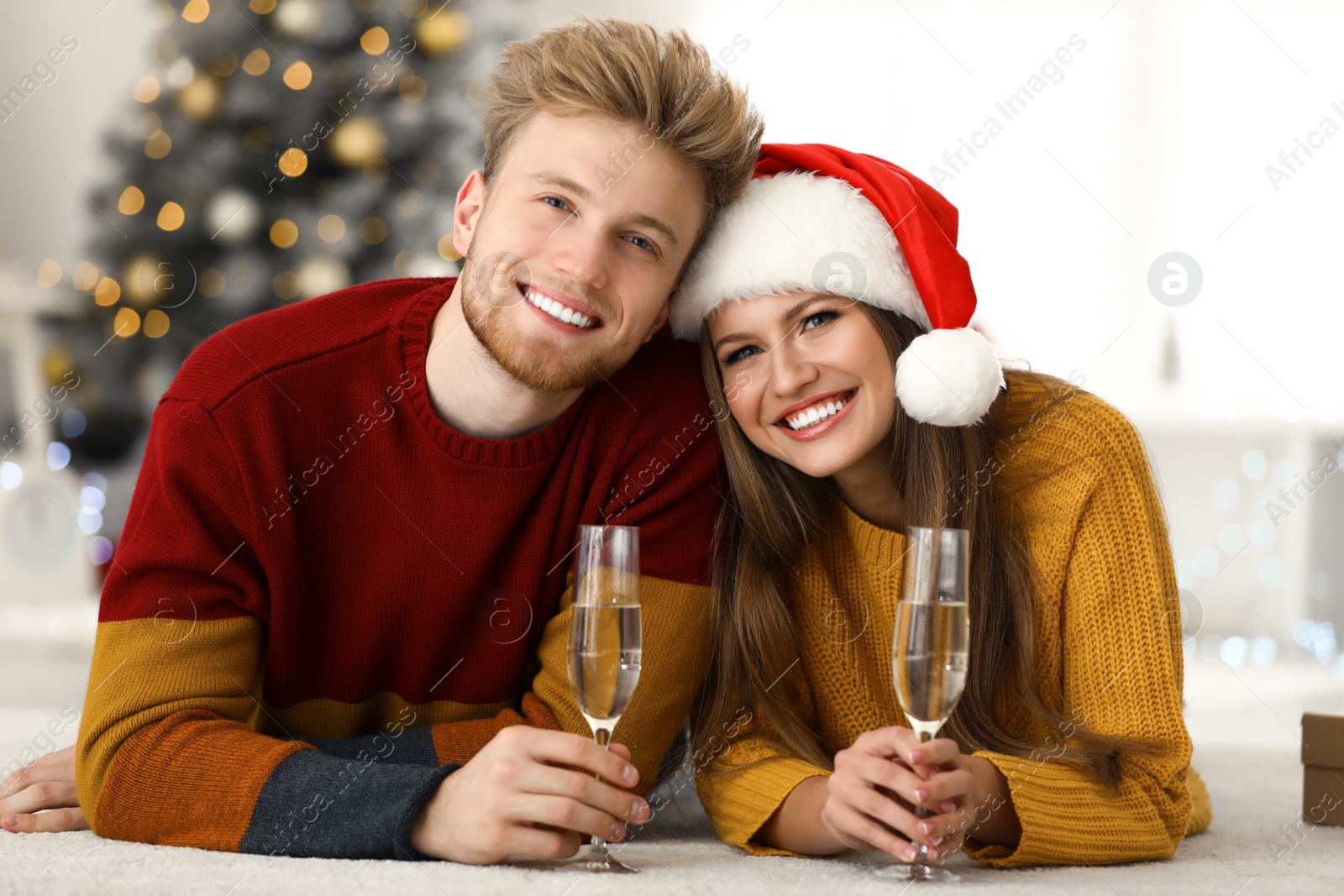 Photo of Happy young couple with glasses of champagne at home. Christmas celebration