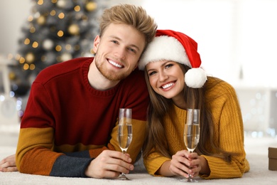 Happy young couple with glasses of champagne at home. Christmas celebration