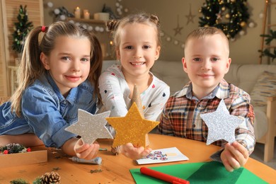 Photo of Cute little children with beautiful stars at home. Making Christmas decor