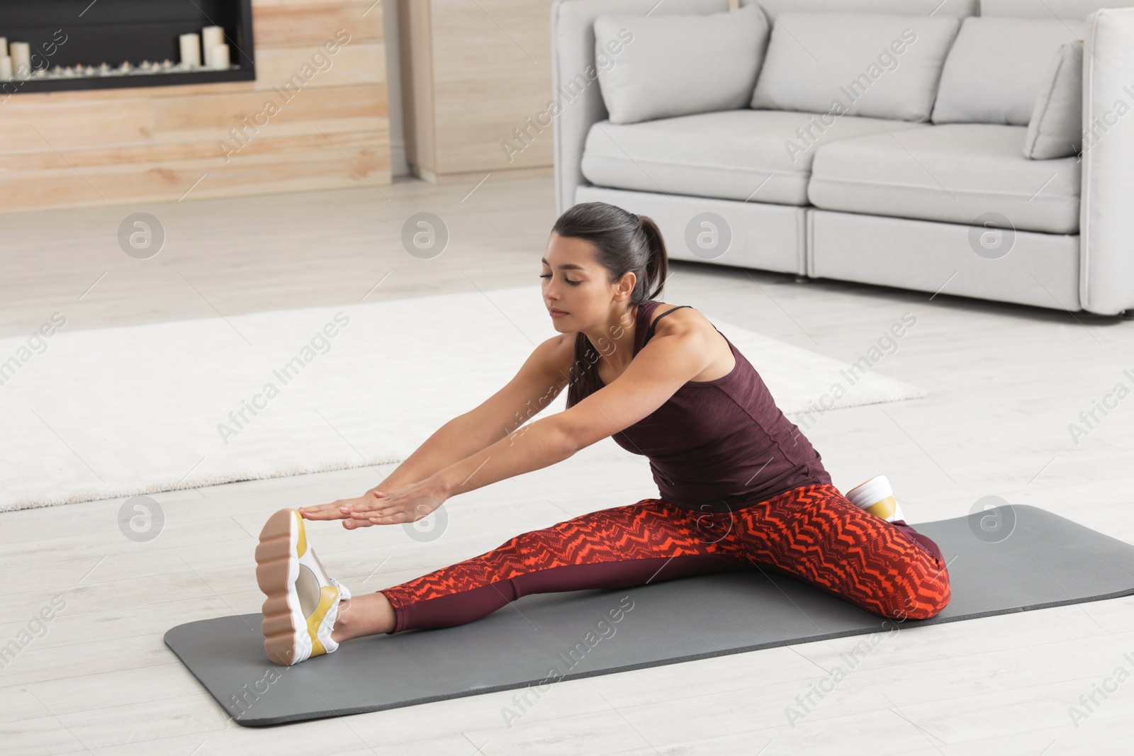 Photo of Young woman in fitness clothes doing exercise at home