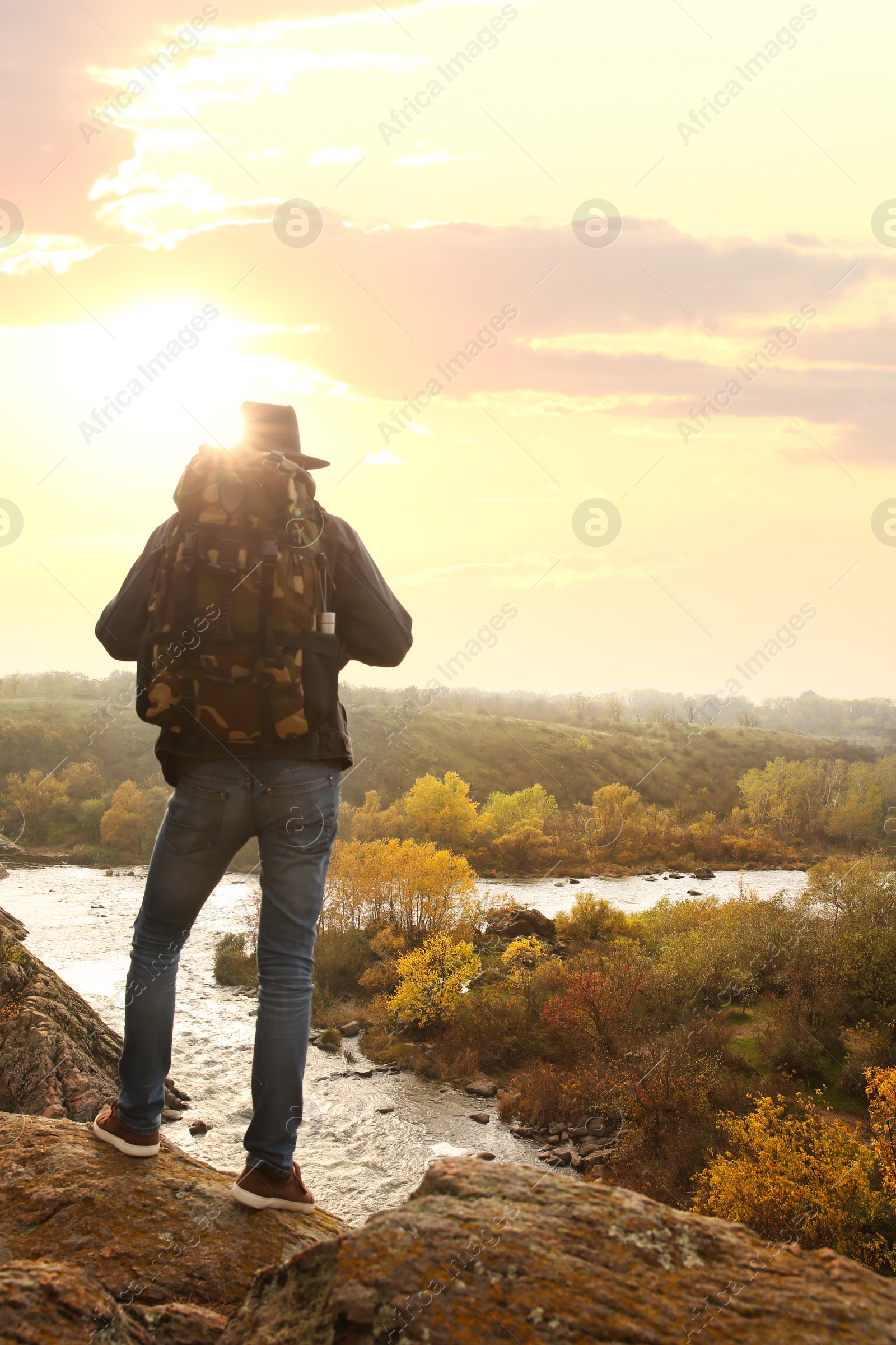 Photo of Traveler with backpack enjoying beautiful view near mountain river. Autumn vacation