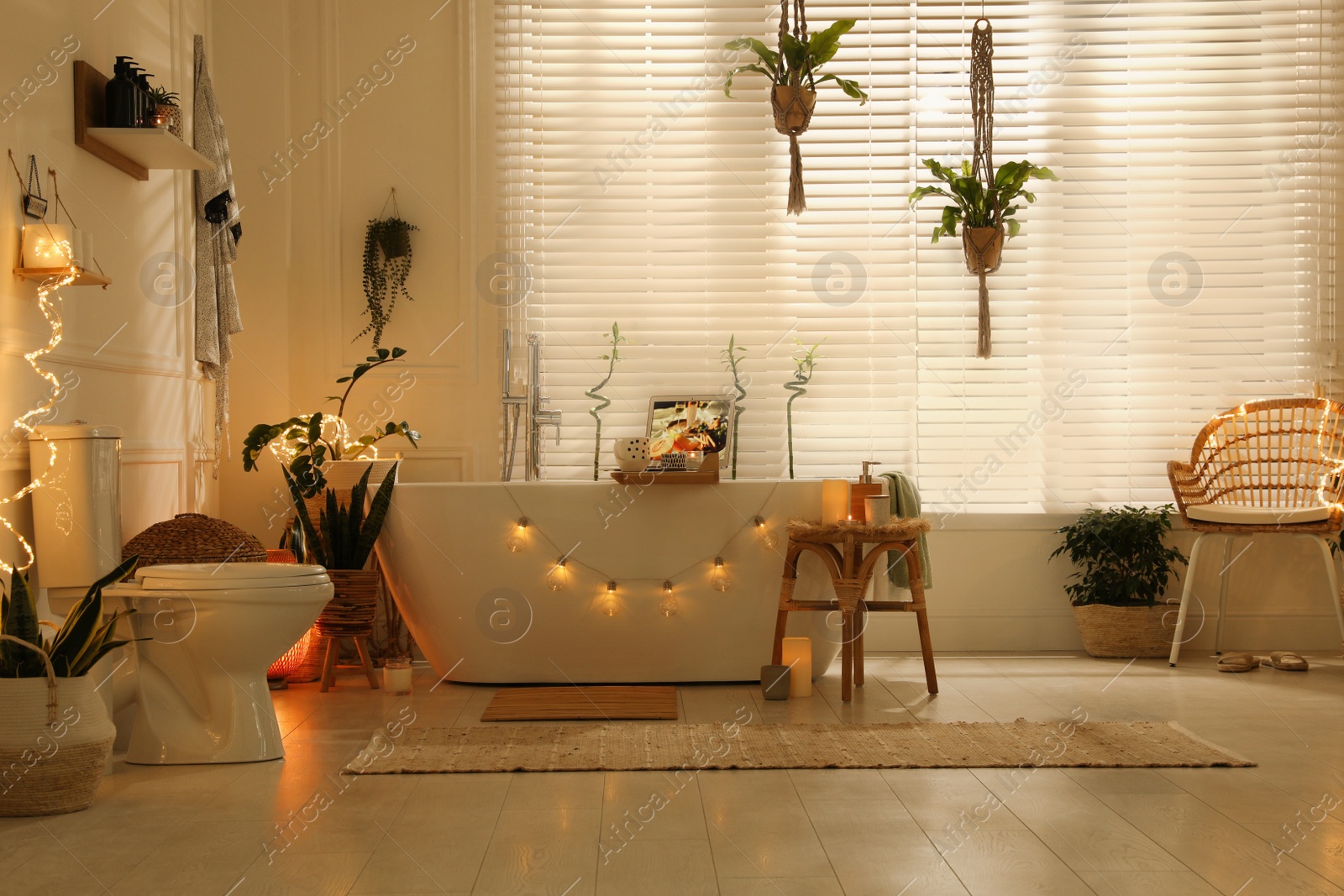 Photo of Stylish bathroom interior with green houseplants and string lights. Idea for design