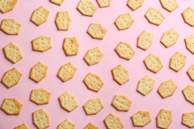 Delicious crackers on pink background, flat lay