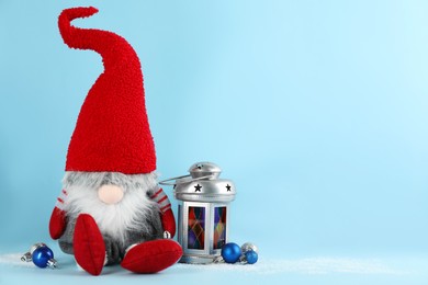 Photo of Cute Christmas gnome, festive balls and lantern on light blue background. Space for text