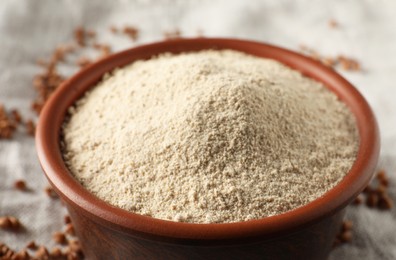 Photo of Bowl of buckwheat flour on cloth, closeup