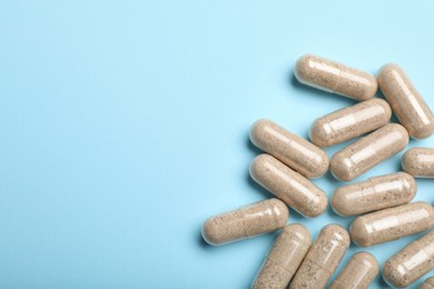 Photo of Many gelatin capsules on light blue background, flat lay. Space for text