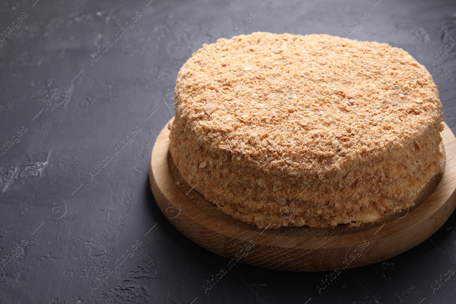 Photo of Delicious Napoleon cake on black table, closeup. Space for text