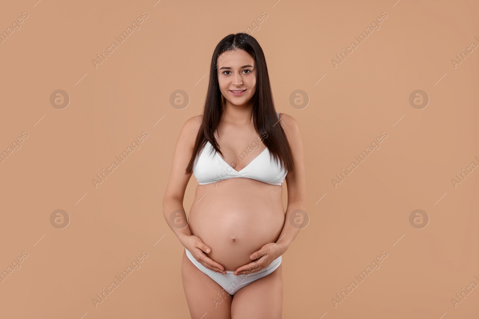 Photo of Beautiful pregnant woman in stylish comfortable underwear on beige background