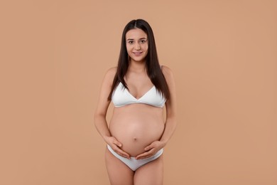 Photo of Beautiful pregnant woman in stylish comfortable underwear on beige background