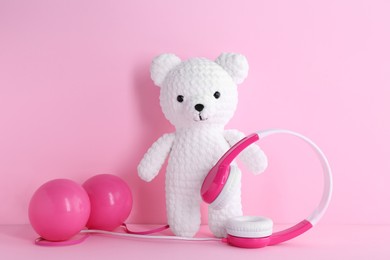 Baby songs. Toy bear, headphones and balls on pink background