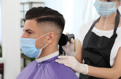 Photo of Professional stylist working with client in salon. Hairdressing services during Coronavirus quarantine