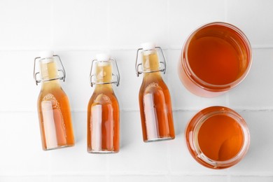 Photo of Tasty kombucha on white tiled table, flat lay