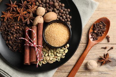 Dishware with different spices on wooden table, flat lay