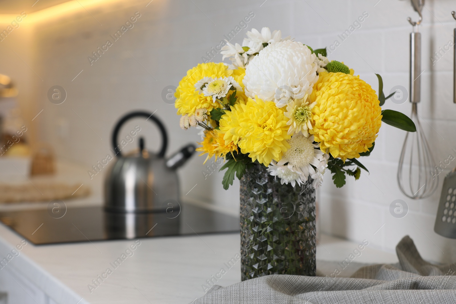 Photo of Bouquet of beautiful chrysanthemum flowers on countertop in kitchen, space for text