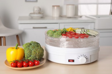 Photo of Vegetables and fruit dehydrator machine on wooden table in kitchen