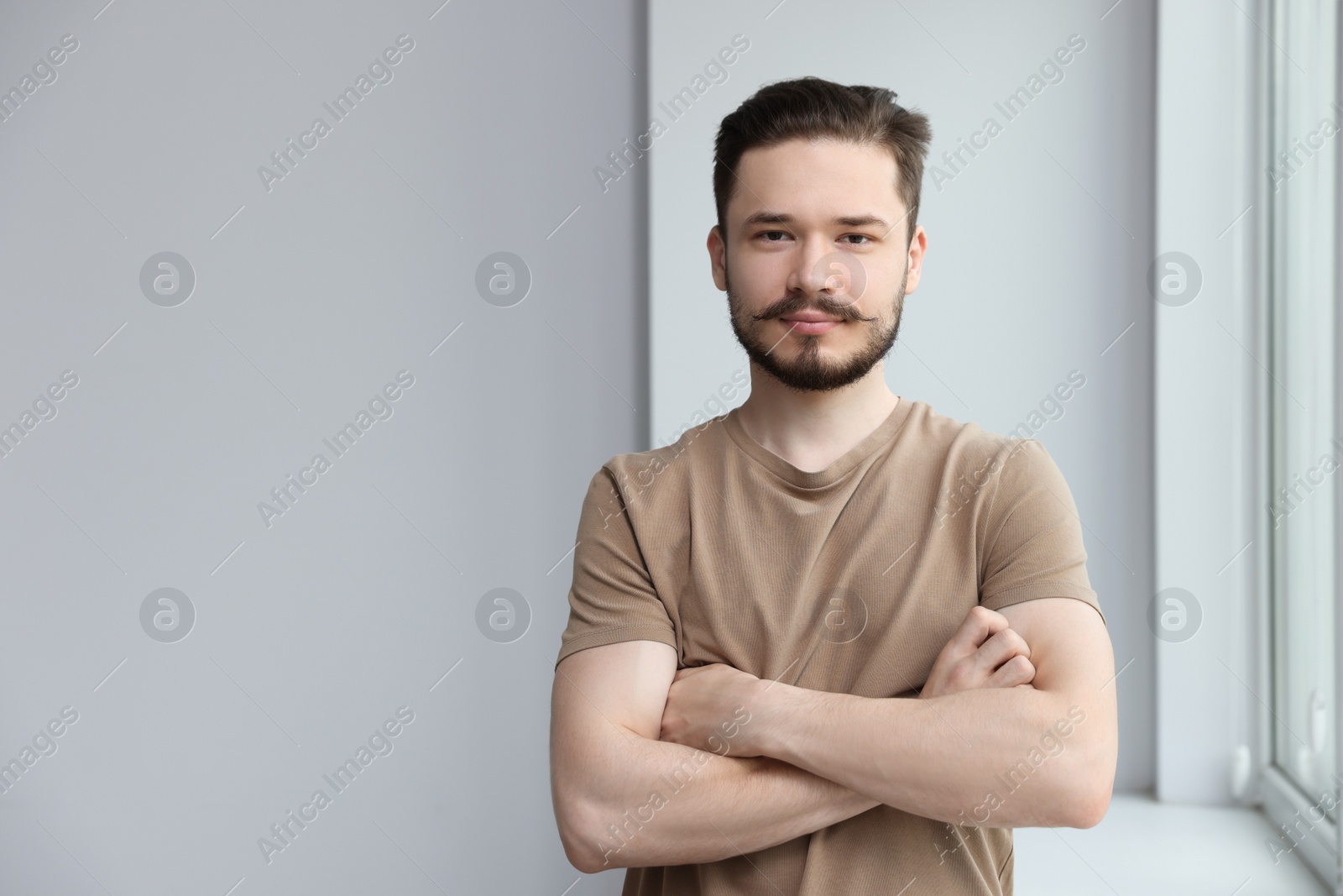 Photo of Handsome man near window indoors. Space for text