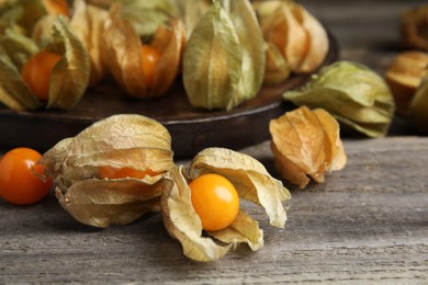 Ripe physalis fruits with dry husk on wooden table, closeup