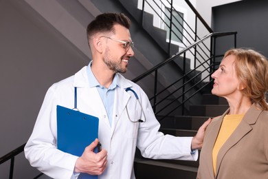 Photo of Happy doctor with clipboard and patient in clinic