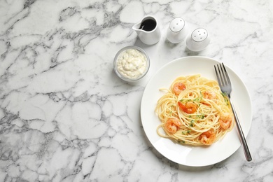 Plate with spaghetti and shrimps on light background, top view