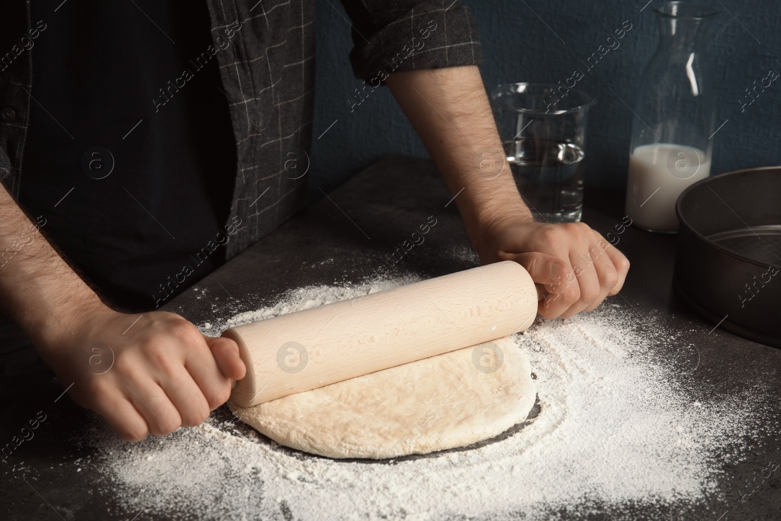 Photo of Man rolling dough for pizza on table