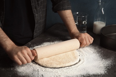 Man rolling dough for pizza on table