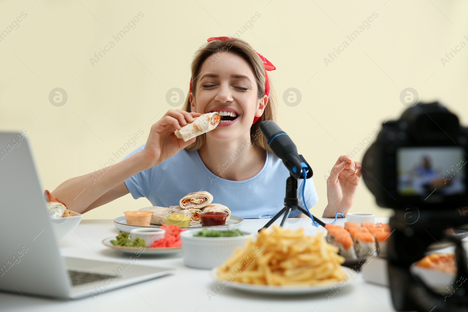 Photo of Food blogger recording eating show on camera against light background. Mukbang vlog