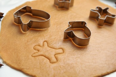 Photo of Dough and cookie cutters on white table, closeup. Christmas biscuits