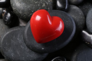 Photo of Red decorative heart on pebble stones, closeup