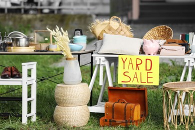 Photo of Table with different stuff and sign Yard sale outdoors