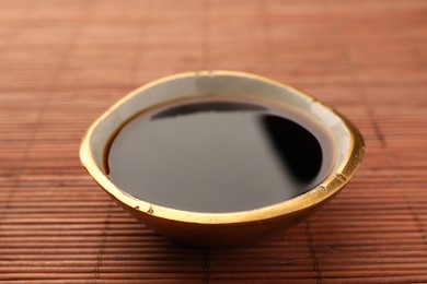 Bowl of soy sauce on bamboo mat, closeup